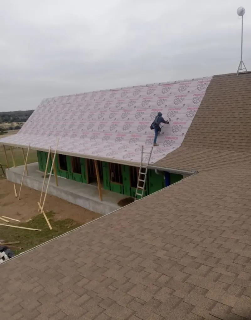 Worker preparing underlayment for a metal roof installation in Menifee